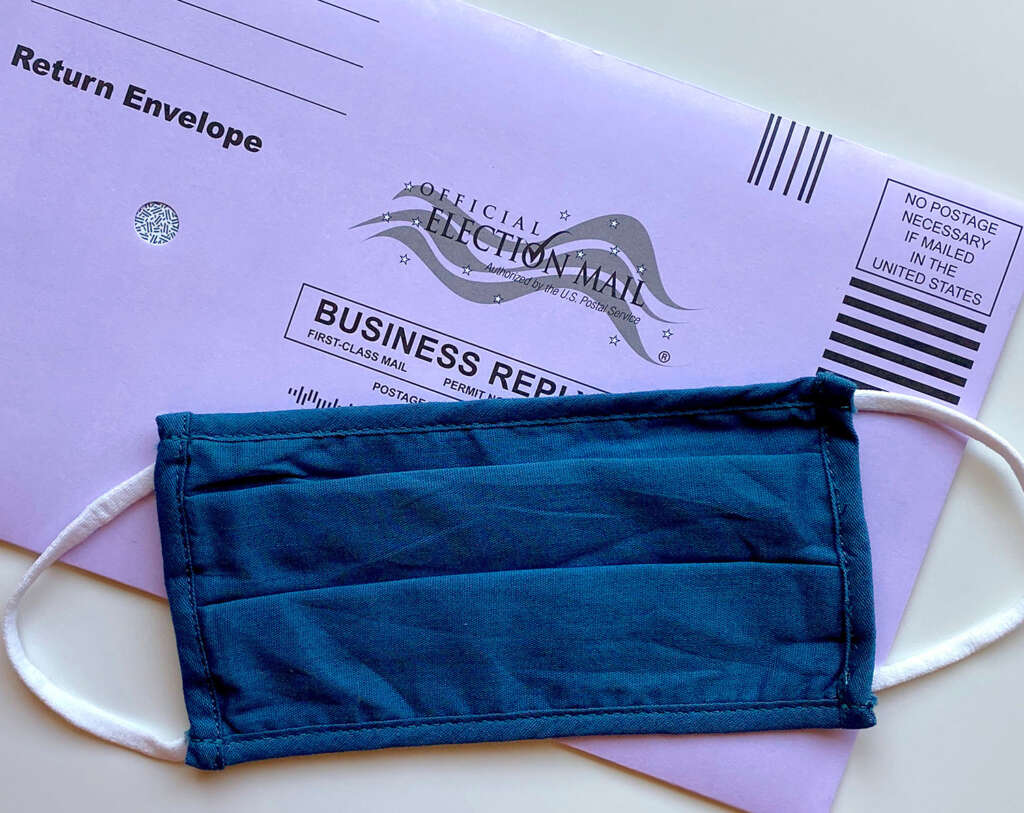 US Ballot envelope and COVID face mask on a table