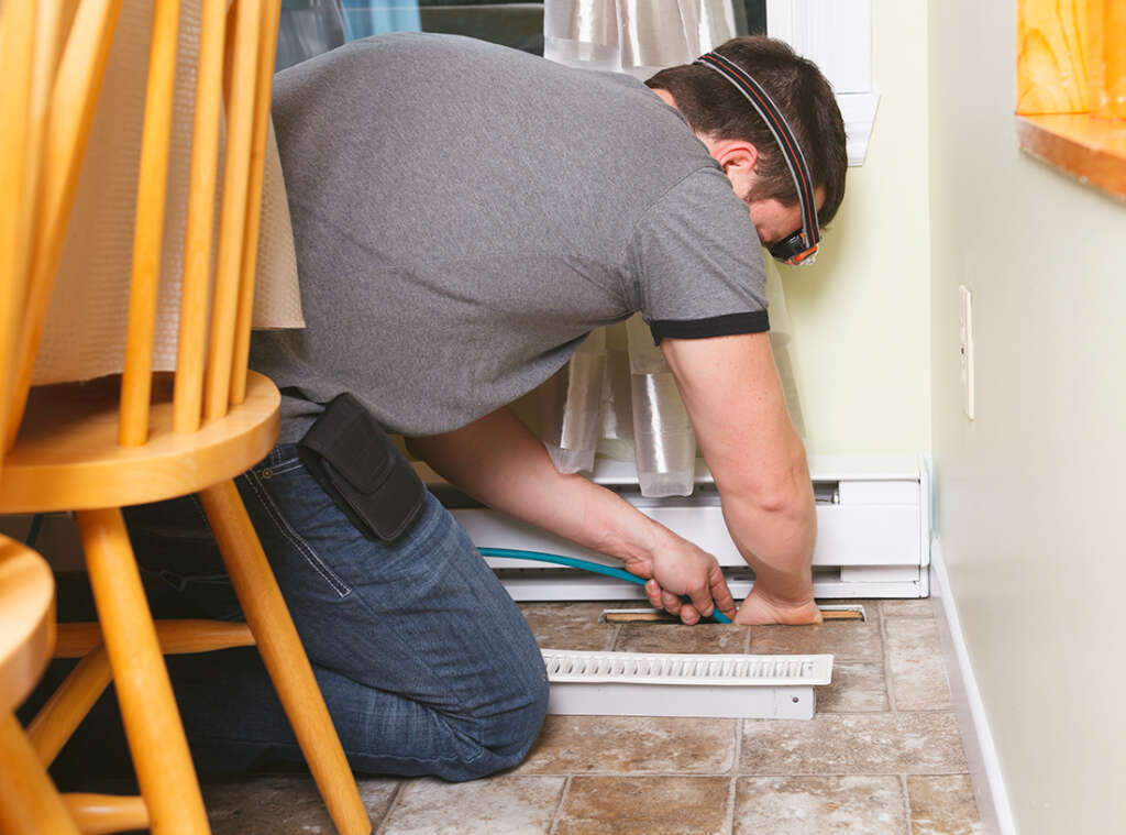 HVAC tech applies aerosol disinfectant to an air duct