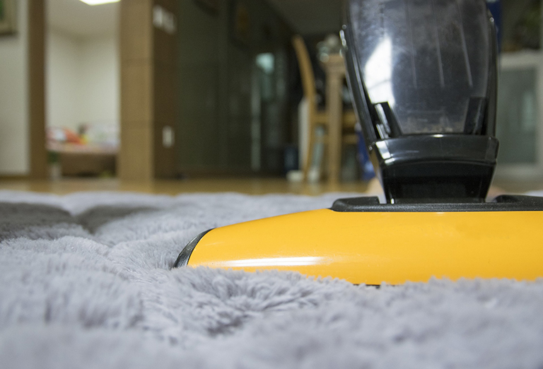 Yellow vacuum cleaner on a fuzzy rug