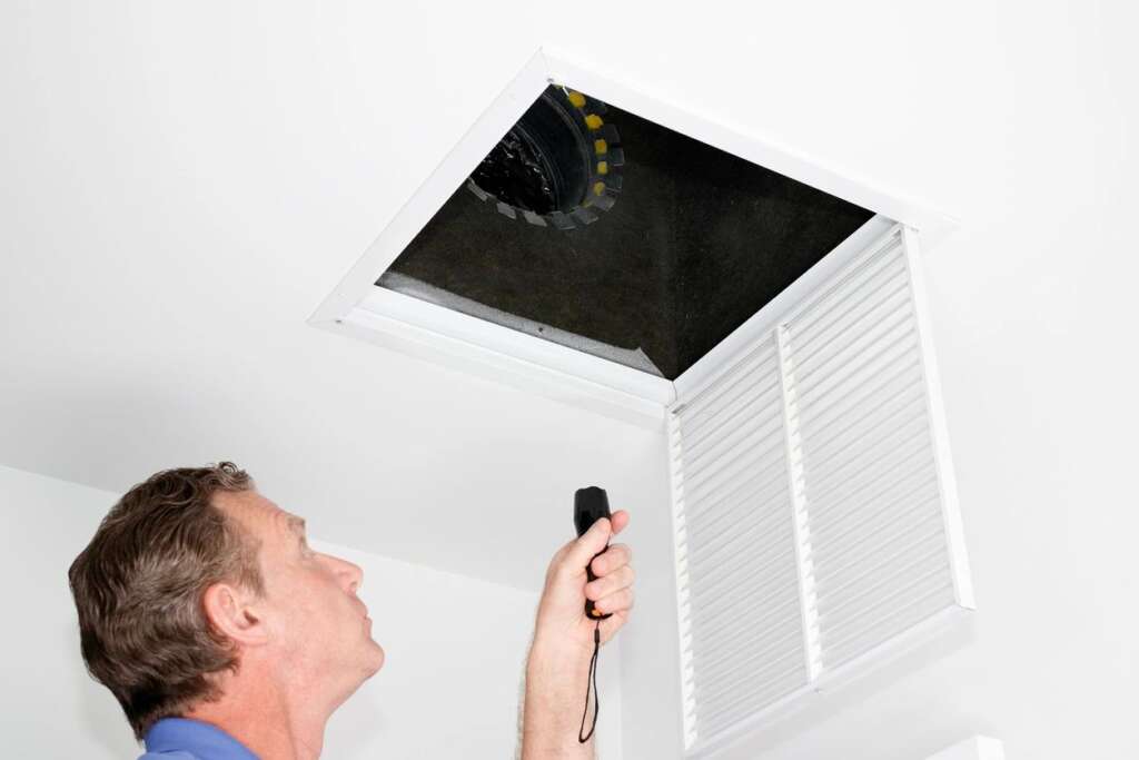 Tech inspecting ceiling air duct in home